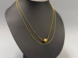 a gold necklace on a mannequin neck with a black background