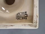 a small white plate with a brown design on it