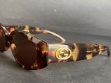 gucci tortoise sunglasses with brown lenses on a gray surface