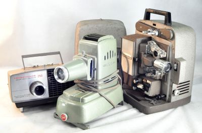 deux vieux appareils photo et un vieux projecteur posés sur une table