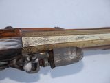 a close up of a gun with a wooden handle on a white surface