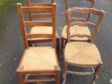 three wooden chairs sitting next to each other in a parking lot