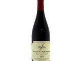 the bottle of red wine is sitting on a white surface