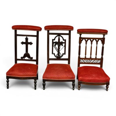 three chairs with red upholstered seats and a cross on the back
