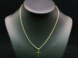 un collier en or orné d'une croix, posé sur le cou d'un mannequin