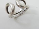 silver ring with a curved design on top of a white surface
