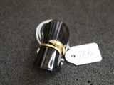 une photo d'une bague noire et dorée à laquelle est accrochée une étiquette