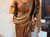 une statue de Jésus debout à côté d'une chaise et d'un miroir