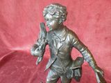 bronze statue of a boy holding a bird on a wooden base