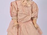 an old fashioned doll with a hat and dress on a stand