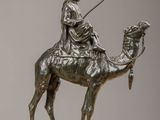 bronze statue of a man riding a camel with a spear in his hand