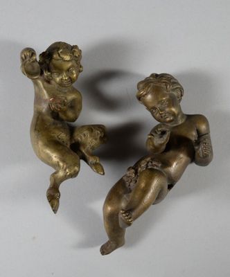 pair of antique bronze figurines of cherensils on a white background