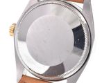 a close up of a watch on a white surface with a brown strap