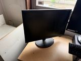 a computer monitor and keyboard on a desk in front of a window