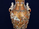 a large vase with a bird on it on a black background