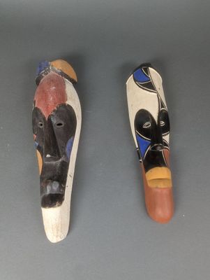 Deux masques en bois sont posés l'un à côté de l'autre sur une table.
