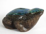 une petite grenouille en céramique posée sur une surface blanche
