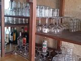 Des bouteilles et des verres sont empilés sur une étagère en bois dans un bar.