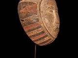 a close up of a wooden mask on a stand against a black background