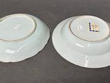 pair of blue and white bowls with gold rims sitting on a table