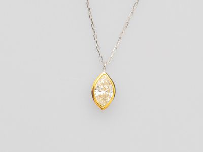 un pendentif en forme de losange jaune et blanc, monté sur une chaîne en argent