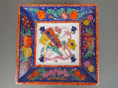 an orange and blue plate with a picture of a bird and flowers on it
