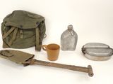 un sac, une bouteille, une pelle et d'autres objets posés sur une surface blanche