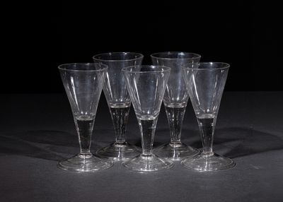 four empty wine glasses sitting on a table with a black background
