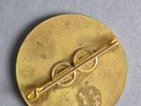 a close up of a gold pin with a pair of scissors on it