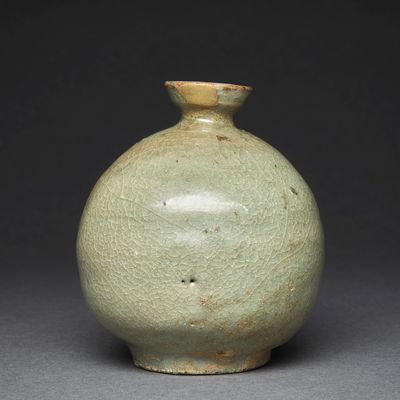 an old green vase sitting on top of a table next to a black background