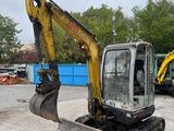 a yellow and black excavator sitting in a parking lot
