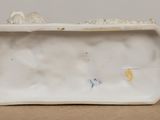 a white vase with a bird on it sitting on a table