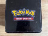 une boîte en fer-blanc noire sur laquelle figure le logo du jeu de cartes à collectionner Pokémon