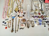 many different necklaces and bracelets laid out on a table