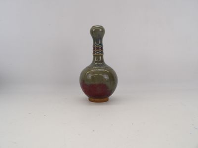 un petit vase posé sur une surface blanche