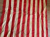 un vieux drapeau américain rouge et blanc accroché à un mur en bois