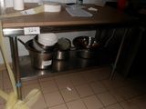 une photo d'une cuisine avec une table sur laquelle sont posés des casseroles et des poêles