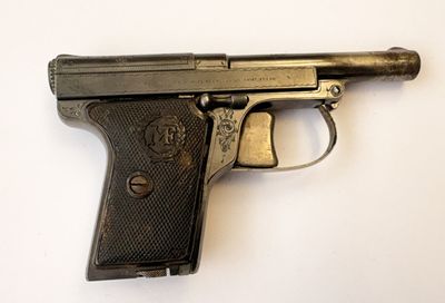 un vieux pistolet avec un canon en métal posé sur une surface blanche