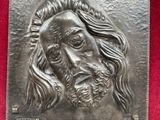 a close up of a metal plaque with a jesus face on it