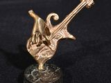 sculpture en bronze représentant une main tenant une guitare, posée sur un socle en marbre