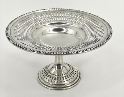 une assiette en argent posée sur un socle, sur fond blanc