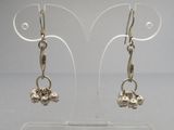 une paire de boucles d'oreilles plaquées argent sur un support en acrylique transparent