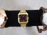 three different watches are displayed on a black display stand