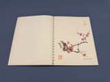 un livre ouvert sur lequel figure l'image d'un oiseau perché sur une branche d'arbre