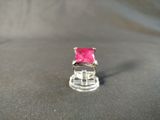 a pink stone ring sitting on top of a glass stand