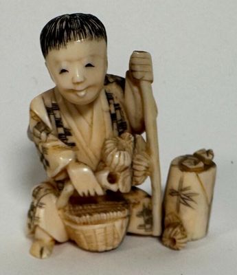 a small figurine of a boy with a basket and a stick