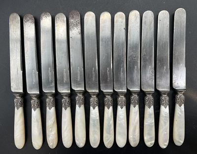 six couteaux en métal argenté aux manches sculptés sont alignés sur une surface noire