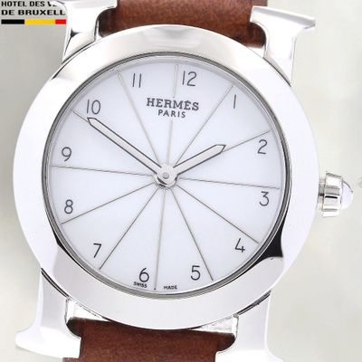 La montre possède un cadran blanc et un bracelet en cuir marron.