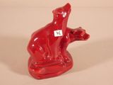 a red bear figurine sitting on a white surface
