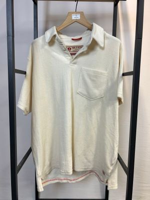 une chemise blanche suspendue à un portant, sur un cintre en bois